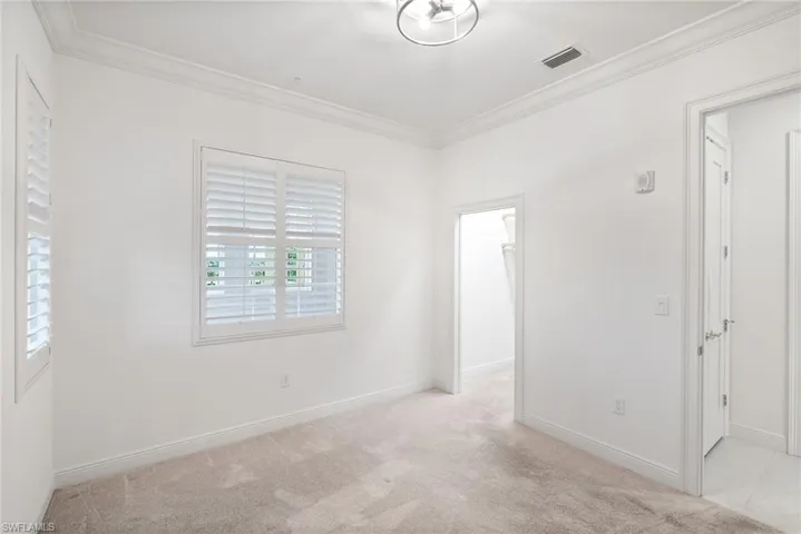 Guest room featuring crown molding and light colored carpet