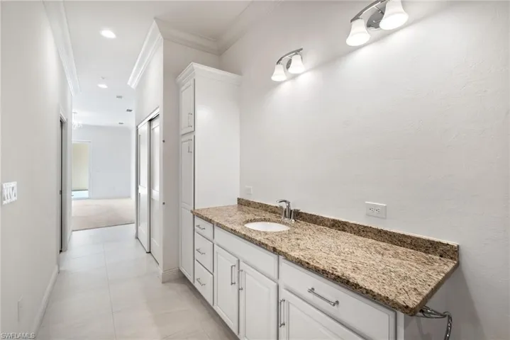 Bathroom featuring tile patterned flooring, vanity, and crown molding