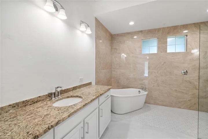 Bathroom featuring vanity, tile patterned flooring, and a bathing tub