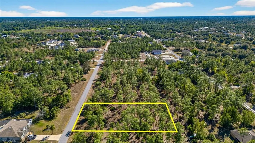 Aerial view of property and surrounding area with property parcel outlined and a forest