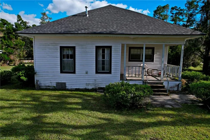 Back of house featuring covered porch and a yard