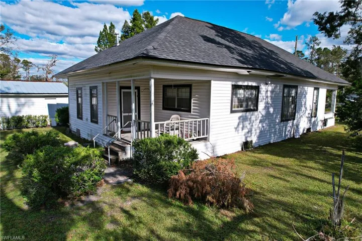 Rear view of property with covered porch and a lawn