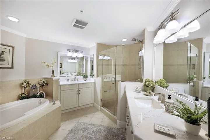 Full bathroom with two vanities, a garden tub, ornamental molding, a stall shower, and light tile patterned floors
