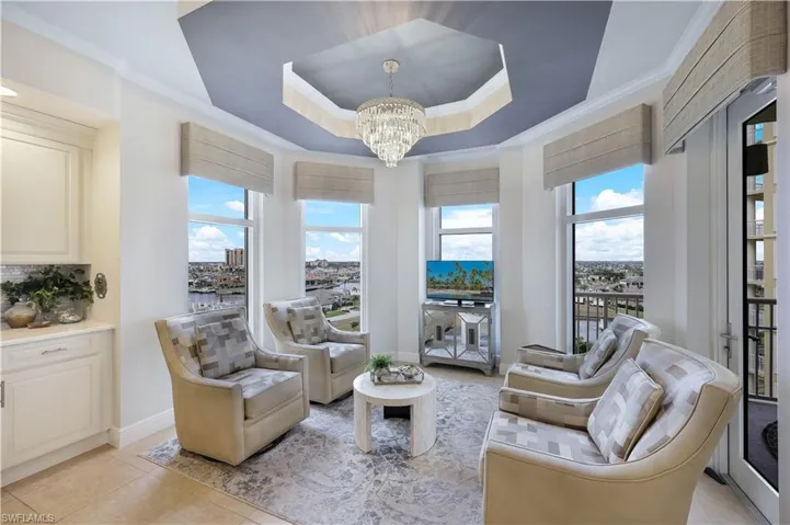 Sitting room featuring a raised ceiling, ornamental molding, light tile patterned flooring, and a chandelier
