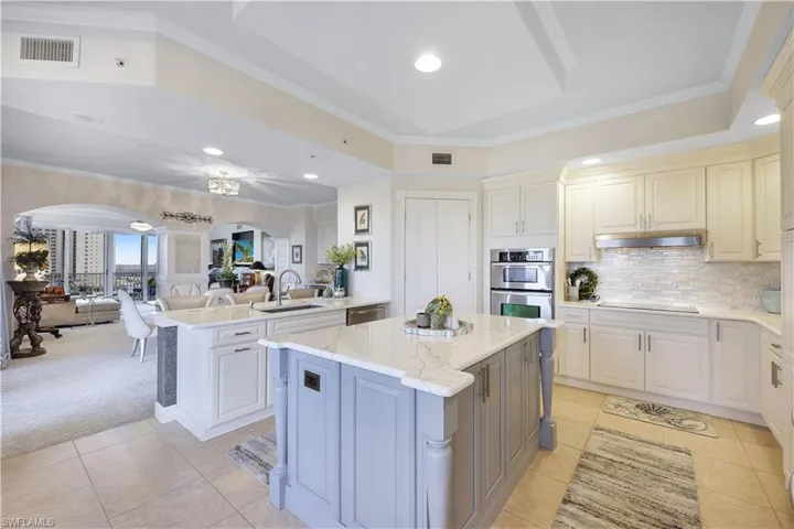Kitchen with ornamental molding, a peninsula, backsplash, open floor plan, and light stone countertops