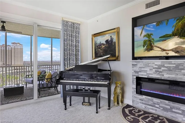 Living area with ornamental molding, a fireplace, and carpet