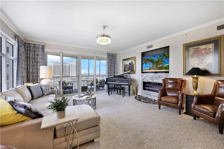 Carpeted living room featuring ornamental molding, a fireplace, and a chandelier