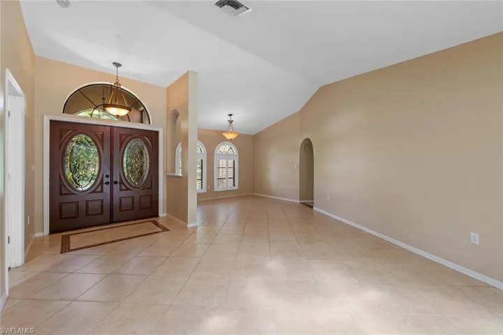Foyer with light tile flooring, french doors, and vaulted ceiling