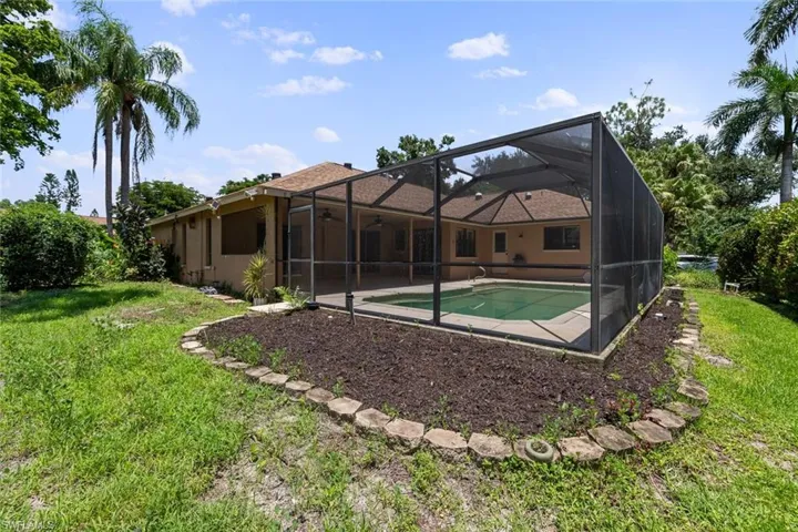 View of pool with a lanai and a lawn