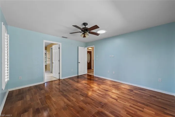 Master bedroom featuring hardwood / wood-style flooring, ensuite bath, and ceiling fan