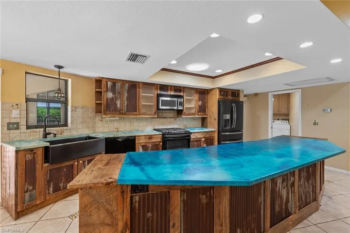 Kitchen featuring dark stainless appliances, pendant lighting, sink, a raised ceiling, and backsplash