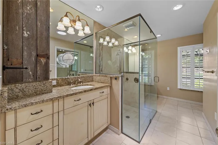 Master Bathroom with tile flooring, dual vanity, an enclosed shower, and walk in closet