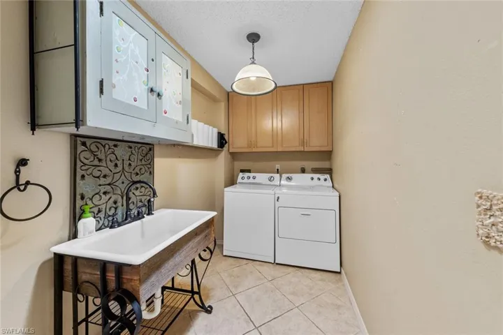 Laundry Room with utility sink, storage cabinets, washer and dryer, light tile floors
