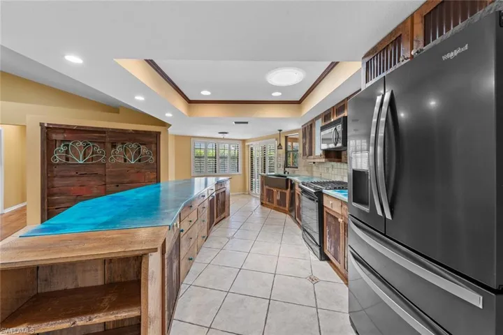 Kitchen with dark stainless steel appliances, decorative backsplash, ornamental molding, sink, and a raised ceiling