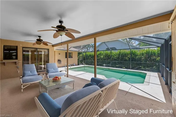 Large covered lanai with view of swimming pool and screened patio with ceiling fan - furniture has been virtuall staged