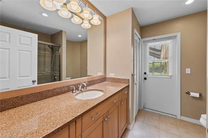 Guest Bathroom featuring tile floors, toilet, and vanity, door to pool area