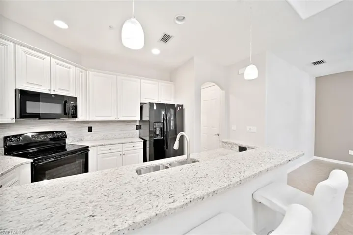 Kitchen featuring sink, white cabinetry, black appliances, and backsplash