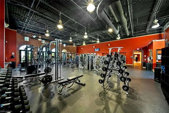 Gym with rail lighting, a towering ceiling, and brick wall