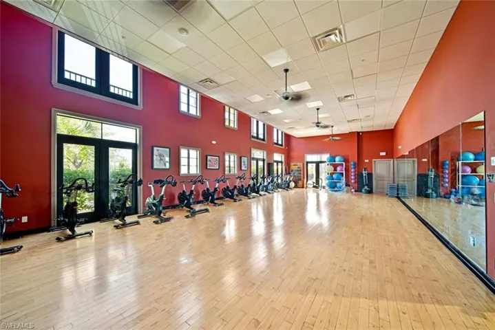 Workout area featuring a high ceiling, light wood-type flooring, a drop ceiling, french doors, and ceiling fan