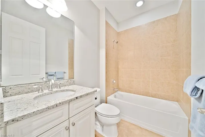 Full bathroom featuring tiled shower / bath, toilet, tile patterned floors, and vanity