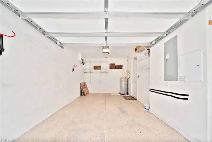 Garage with a garage door opener, water heater, and electric panel