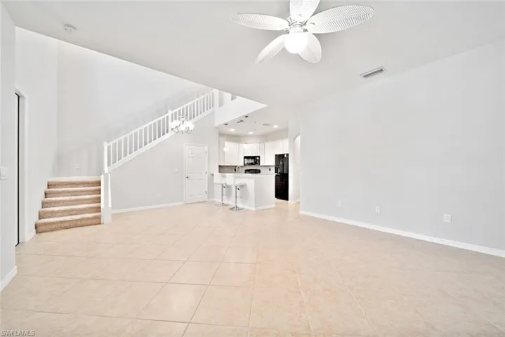 Unfurnished living room featuring ceiling fan with notable chandelier and light tile patterned flooring