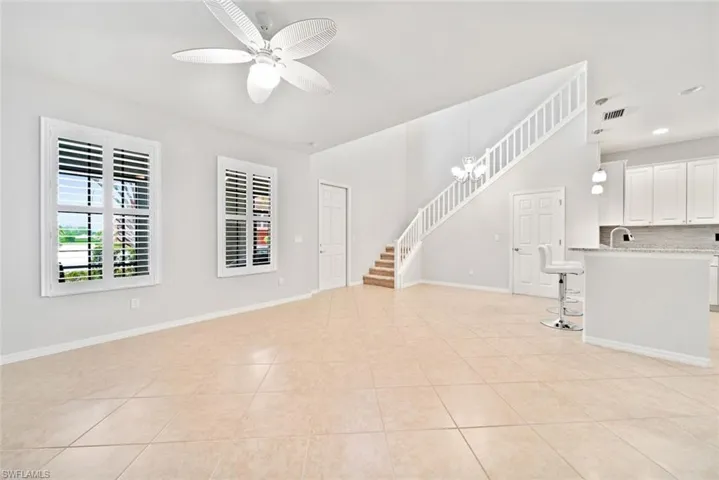 Tiled spare room featuring ceiling fan with notable chandelier and sink