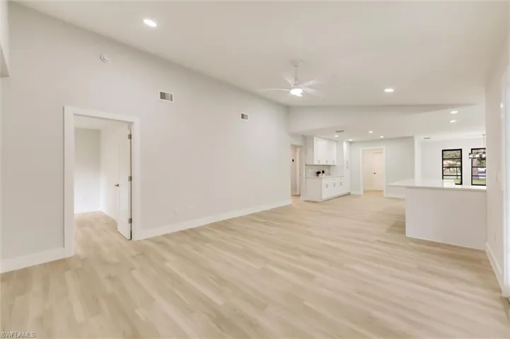 Unfurnished living room with ceiling fan, lofted ceiling, and light wood-type flooring