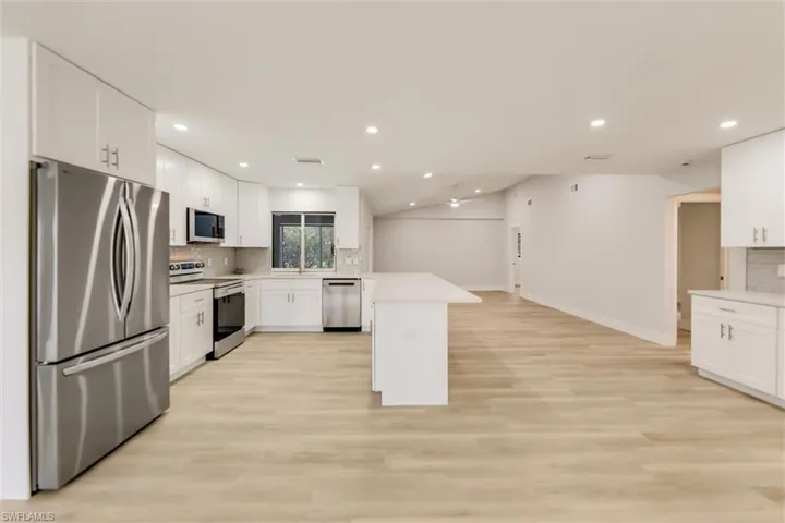 Kitchen featuring sink, appliances with stainless steel finishes, tasteful backsplash, white cabinets, and light wood-type flooring