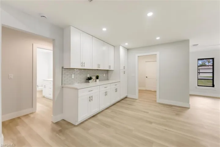 Kitchen with tasteful backsplash, white cabinets, and light hardwood / wood-style flooring