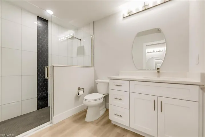Bathroom featuring vanity, wood-type flooring, toilet, and walk in shower