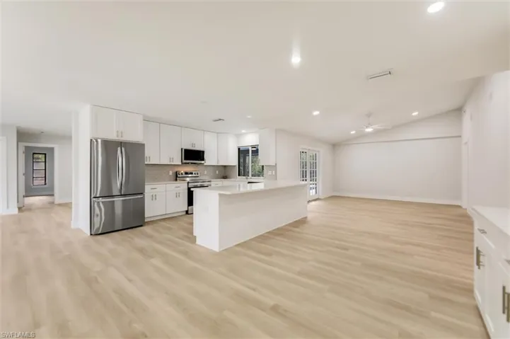 Kitchen featuring a wealth of natural light, light wood-type flooring, white cabinets, and appliances with stainless steel finishes