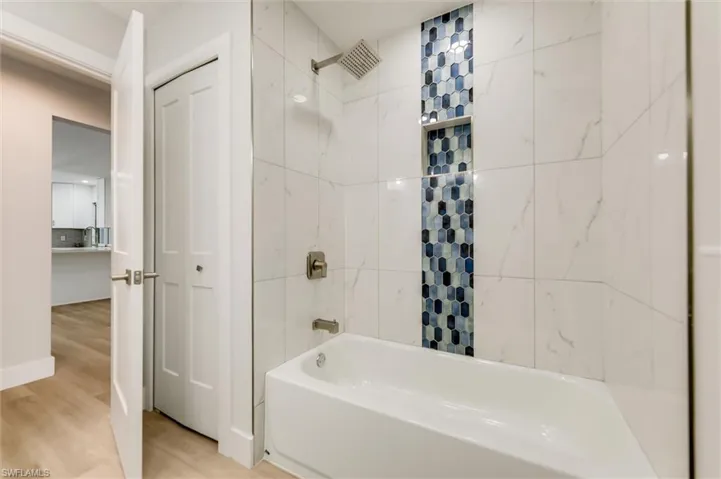Bathroom featuring tiled shower / bath, hardwood / wood-style floors, and tile walls