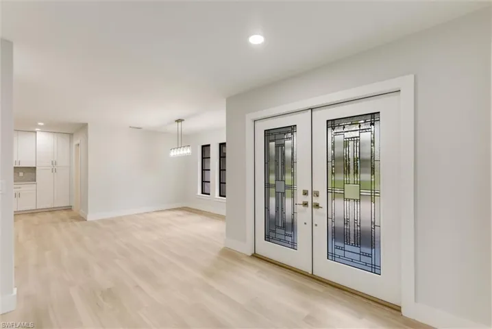 Doorway with an inviting chandelier, light hardwood / wood-style floors, and french doors