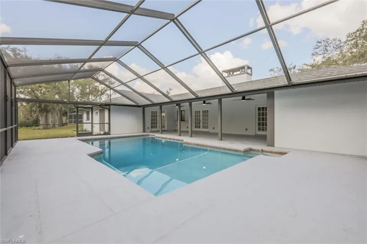 View of pool with a patio, a lanai, ceiling fan, and french doors