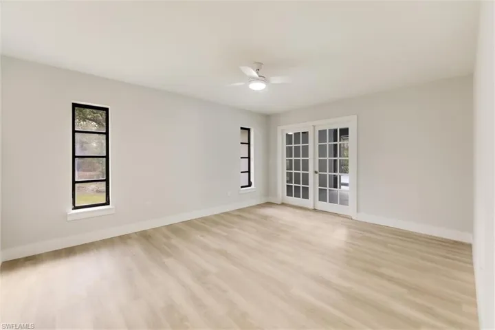 Empty room with light hardwood / wood-style flooring, ceiling fan, and french doors