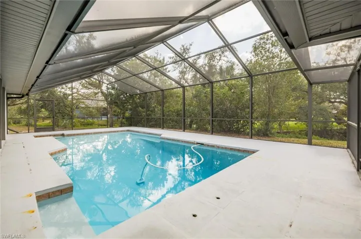 View of swimming pool featuring a patio and glass enclosure