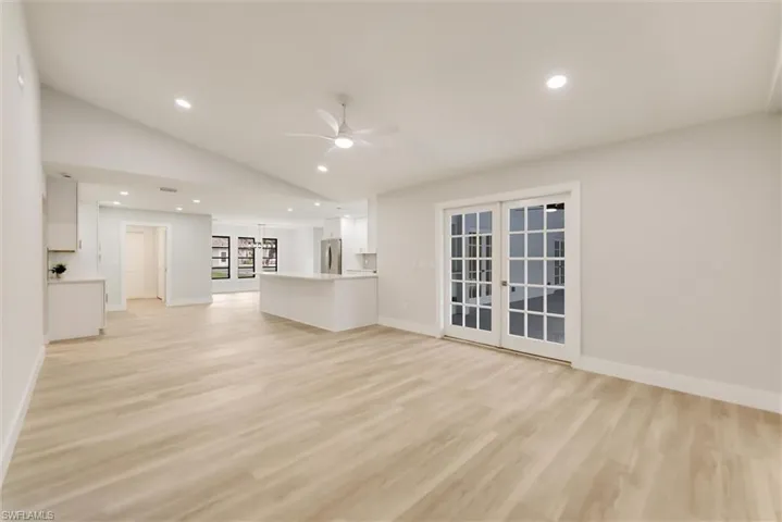 Unfurnished living room featuring lofted ceiling, light hardwood / wood-style flooring, ceiling fan, and french doors