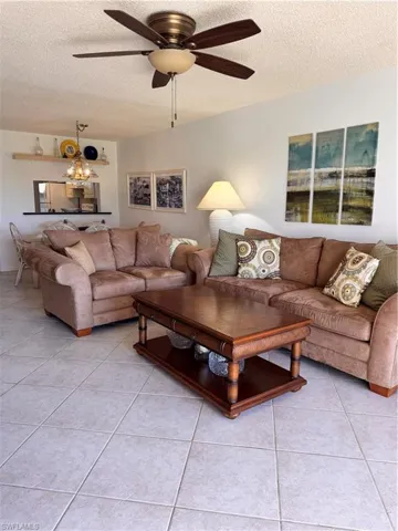 Tiled living room featuring ceiling fan and a textured ceiling