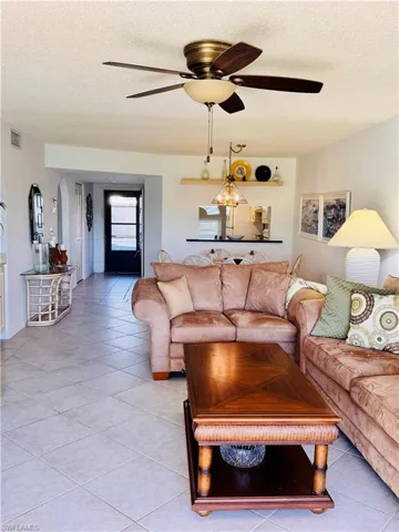 Tiled living room with ceiling fan and a textured ceiling