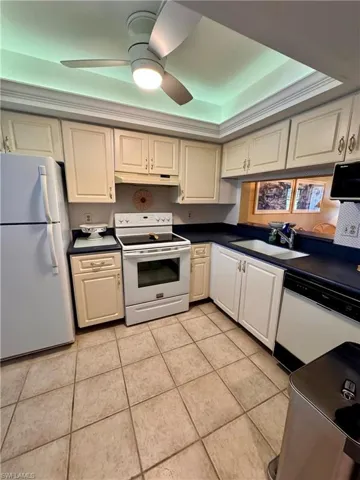 Kitchen with ceiling fan, white appliances, sink, and light tile patterned floors