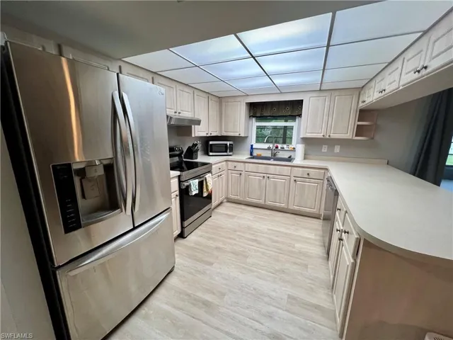 Kitchen featuring luxury vinyl plank floors, appliances with stainless steel finishes, sink, and a paneled ceiling