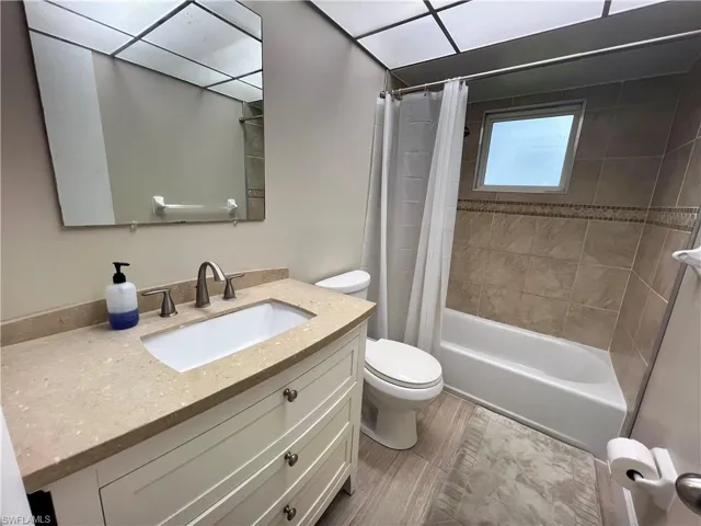 Full bathroom featuring vanity, luxury vinyl plank floors, toilet, and shower / tub combo