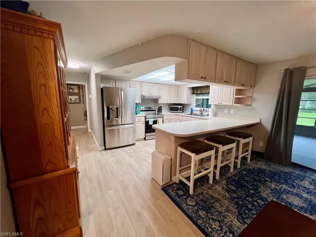 Kitchen featuring a breakfast bar area, stainless steel appliances, sink, kitchen peninsula, and luxury vinyl plank flooring