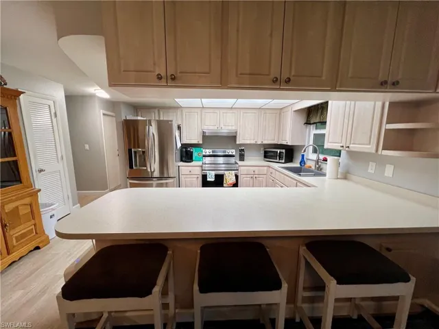 Kitchen featuring sink, a breakfast bar area, appliances with stainless steel finishes, luxury vinyl plank flooring, and kitchen peninsula