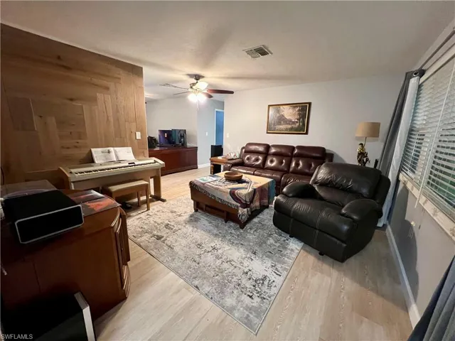 Living room featuring wood walls, luxury vinyl plank flooring, and ceiling fan