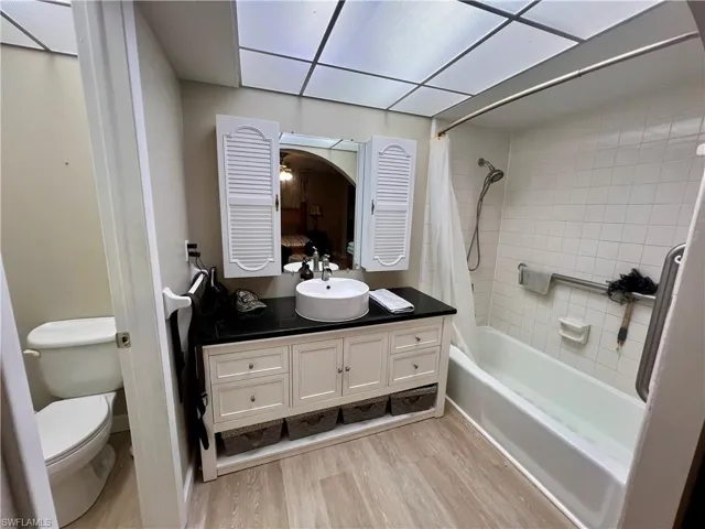 Full bathroom featuring shower / tub combo with curtain, vanity, toilet, and luxury vinyl plank floors