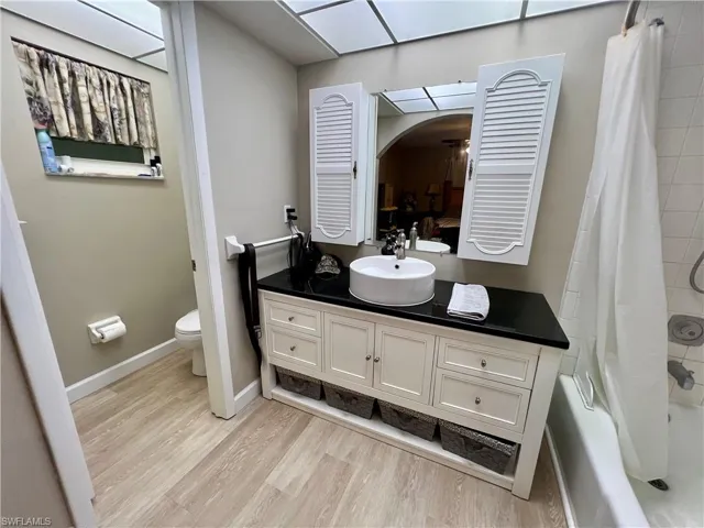 Full bathroom with shower / tub combo, luxury vinyl plank flooring, toilet, and vanity