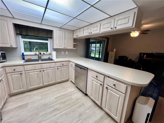 Kitchen with kitchen peninsula, ceiling fan, stainless steel appliances, luxury vinyl plank floors, and sink
