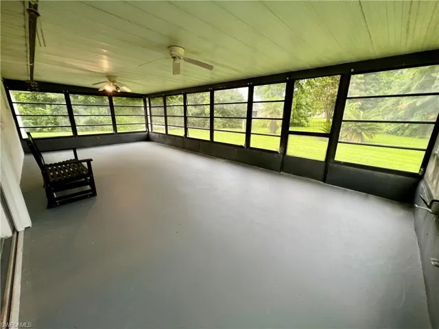 Unfurnished sunroom featuring a healthy amount of sunlight, wood ceiling, and ceiling fan